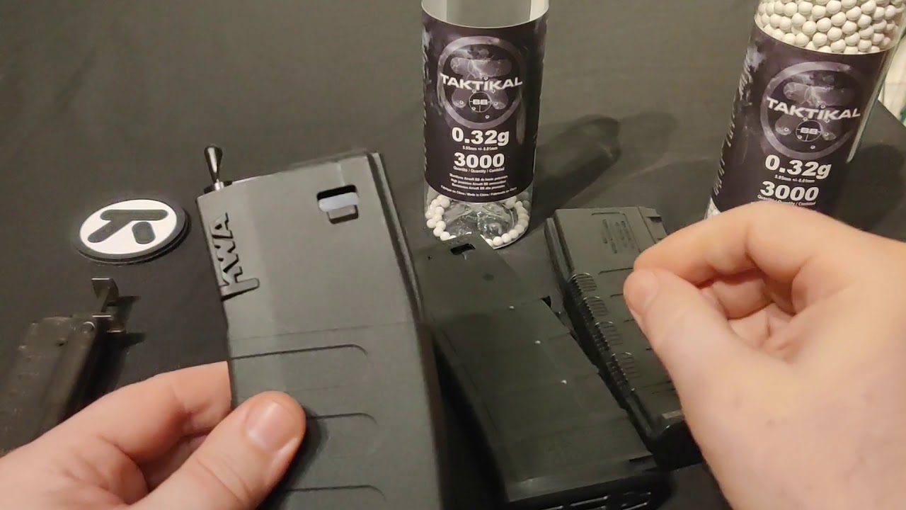 Ręce nabijające magazynki Hi-Cap kulkami przez otwór w dolnej części