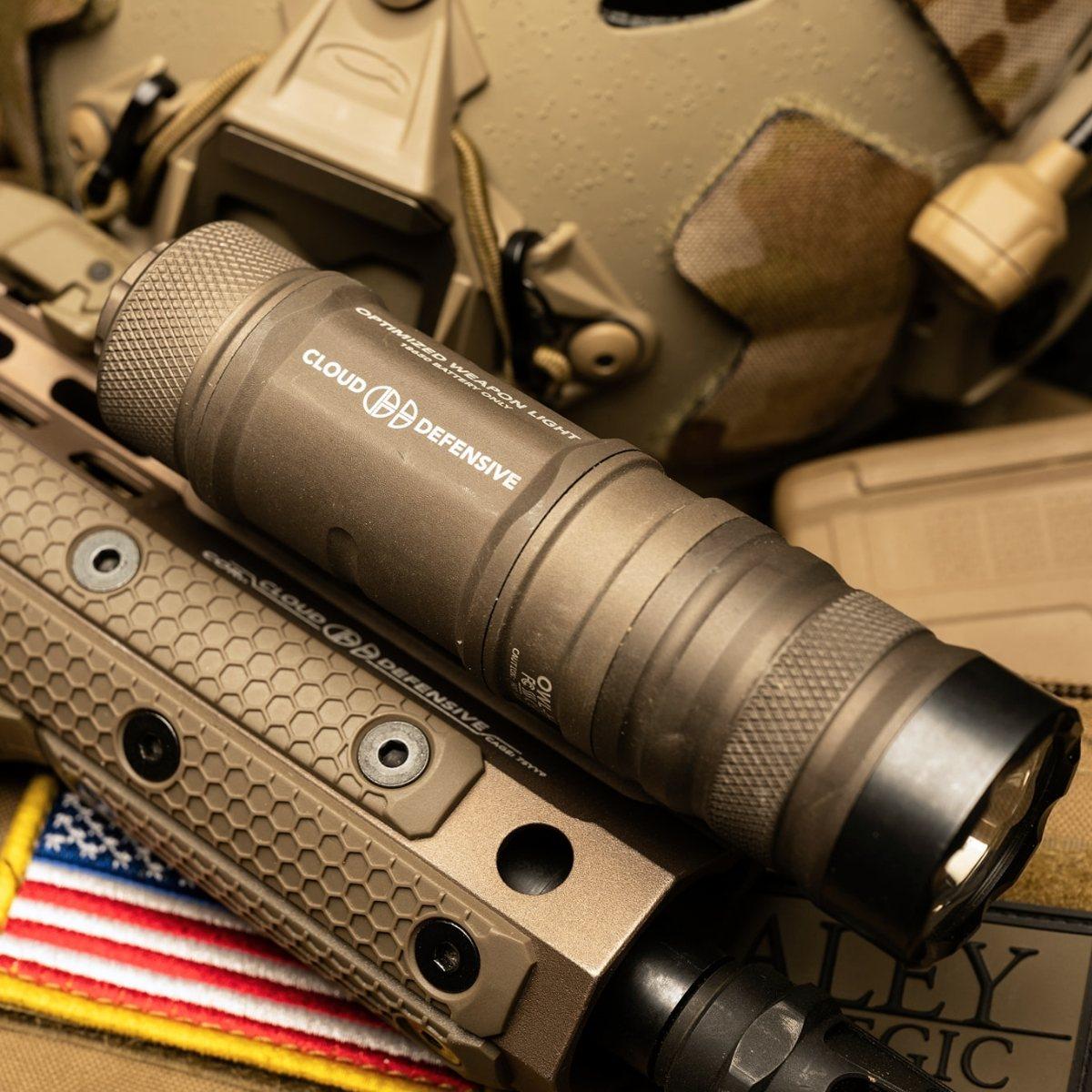 Czarna latarka taktyczna zamontowana na szynie RIS karabinu z jasnym strumieniem światła