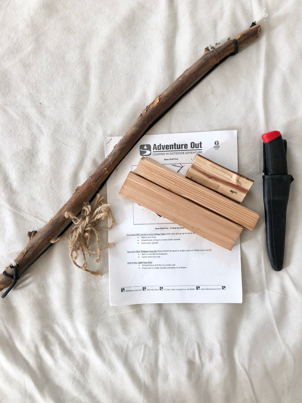 metoda tarcia patykiem do ognia mężczyzna kręci patykiem w wyżłobionej desce drewnianej z naciskiem