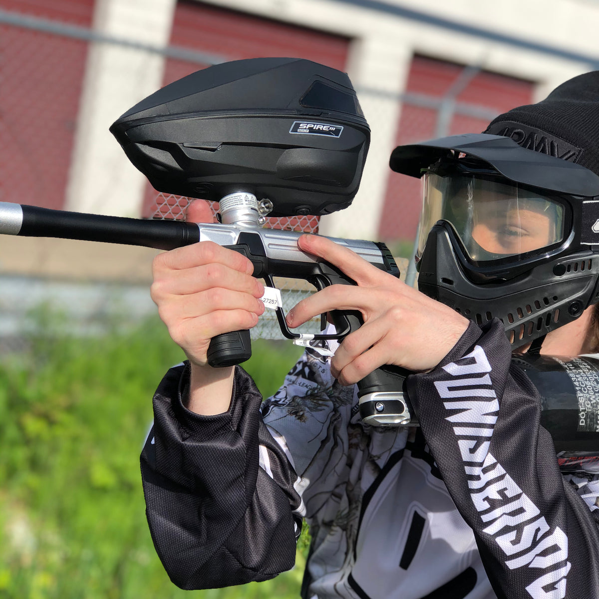 gracz paintball biegnący przez błoto z uniesionym markerem