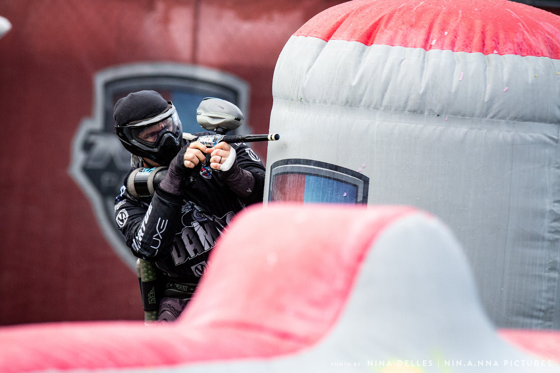 dwoje graczy paintball planujących taktykę za osłoną z napięciem